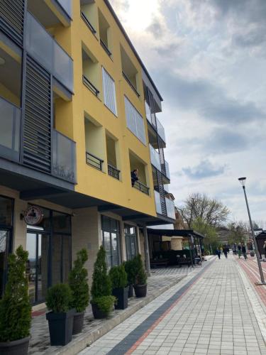 un bâtiment jaune dans une rue avec des plantes en pot dans l'établissement Nest apartman, à Veliko Gradište