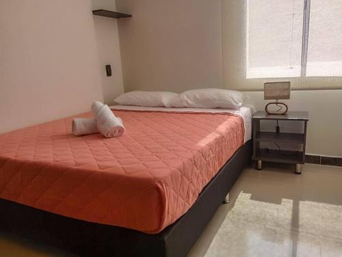 ein Schlafzimmer mit einem Bett mit einer orangefarbenen Bettdecke in der Unterkunft Great location with office near to everything self-checking pool& gym in Medellín