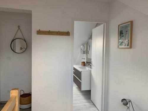 een hal met een badkamer met een wastafel en een spiegel bij Très beau gîte neuf et fonctionnel aux portes du Mans et du circuit in Teloché