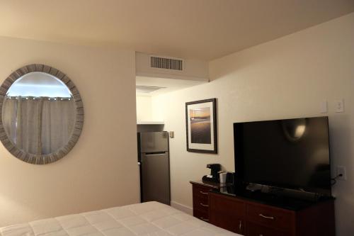 ウィルコックスにあるWillcox Extended Residence Inn and Suitesのベッド、テレビ、鏡が備わる客室です。