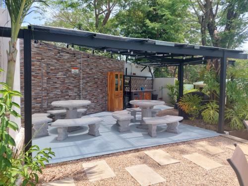 a pergola with picnic tables and benches on a patio at Hotel Carlota Tamarindo in Tamarindo