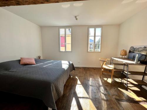 a bedroom with a bed and a desk and windows at Le gîte du bonheur in Bagnères-de-Bigorre
