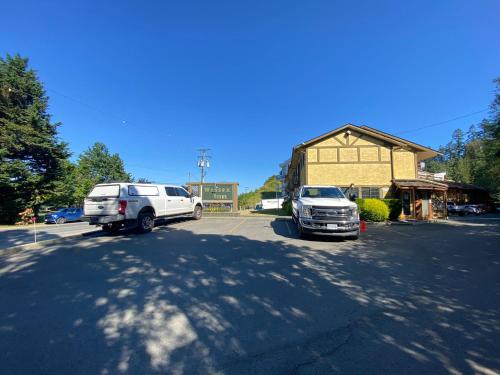 two vehicles parked in a parking lot next to a building at Wessex Inn By The Sea in Cowichan Bay
