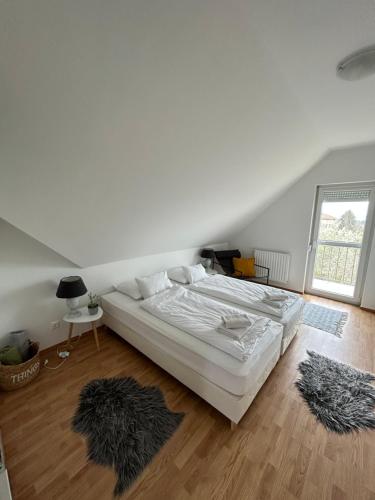 a bedroom with a large white bed and wooden floors at Villa Hegyalja in Balatonkenese