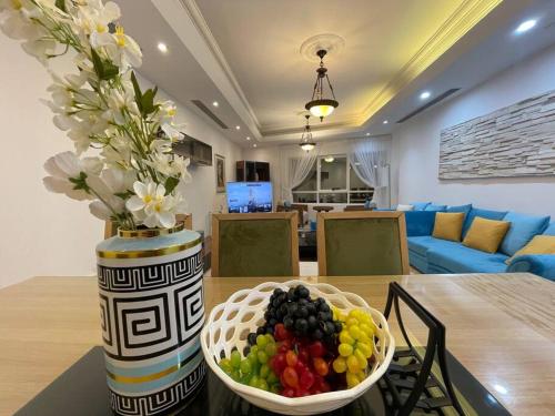 een vaas met bloemen en een fruitschaal op een tafel bij Waterfront Royal 3BR apartment in Sharjah