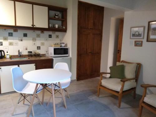 a kitchen with a white table and chairs in a kitchen at Acogedor departamento Los Ranchos in Chacras de Coria