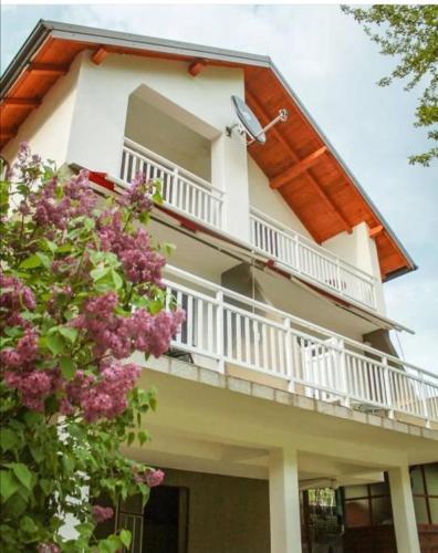 a white house with a balcony and purple flowers at Silent home in Visoko