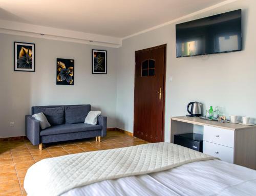 切霍奇內克的住宿－Villa AdaMar - masaże & jacuzzi，一间卧室配有一张床、一张沙发和一台电视。