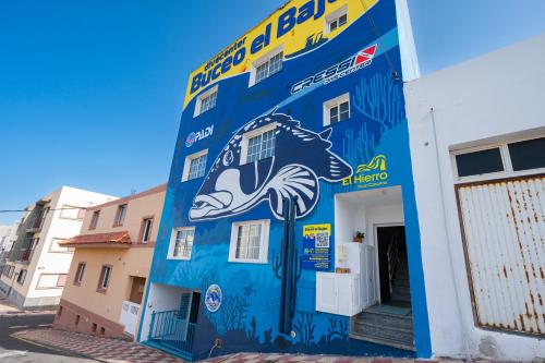 a blue building with a mural of a fish on it at Alojamientos el Bajón in La Restinga