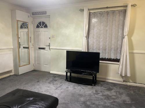 ein Wohnzimmer mit einem Flachbild-TV und einem Sofa in der Unterkunft LONDON 1 BED COSY HOUSE in Norwood