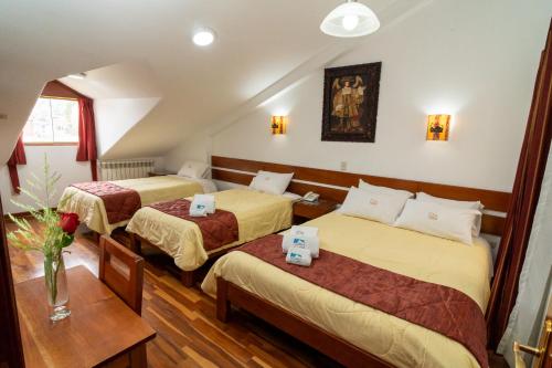 Habitación de hotel con 2 camas y mesa en Kenamari Hotel Cusco, en Cusco