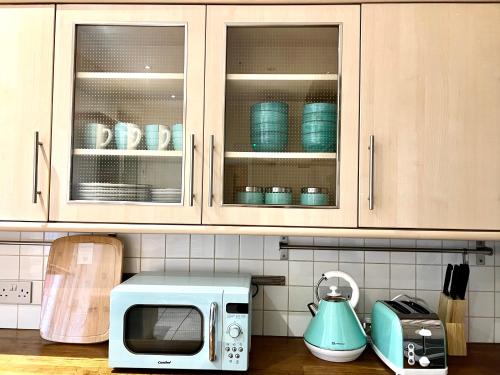 a kitchen counter with a microwave and blue dishes at Aldgate Holiday Rooms in London
