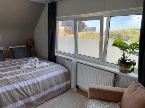 ein Schlafzimmer mit einem Bett und ein Fenster mit einer Pflanze in der Unterkunft Beautiful house at beach, sea and dunes in Wijk aan Zee