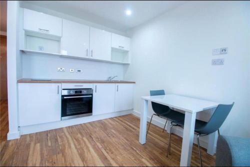 a kitchen with white cabinets and a white table and chairs at Luxury Apartment near Media City in Manchester