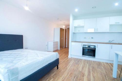 a bedroom with a bed and a kitchen with white cabinets at Luxury Apartment near Media City in Manchester