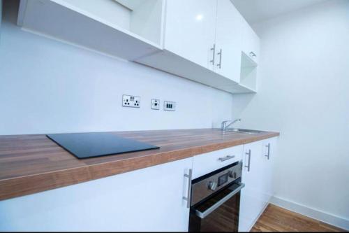 a kitchen with white cabinets and a sink at Luxury Apartment near Media City in Manchester