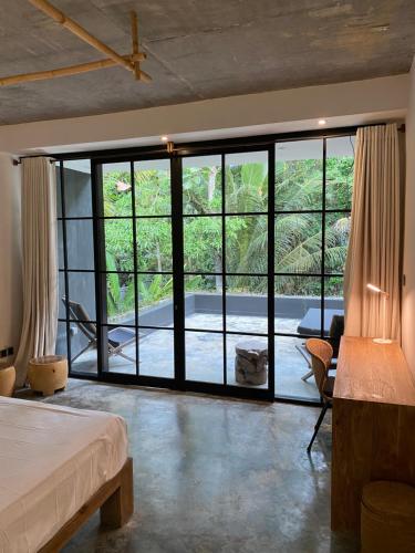 a bedroom with a large glass door leading to a patio at The CIVYT in Ubud