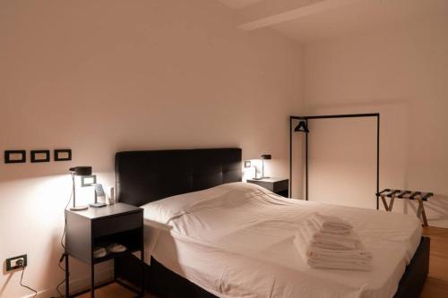 Schlafzimmer mit einem Bett mit weißer Bettwäsche und einem Spiegel in der Unterkunft Piazza Duomo Cathedral View in Brescia