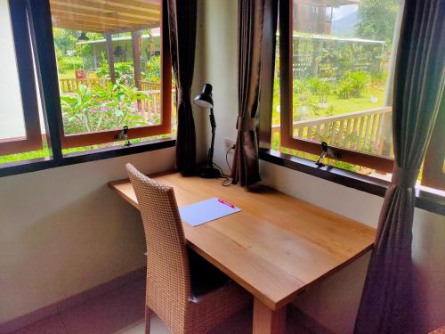 una mesa de madera en una habitación con 2 ventanas en Ilasan cottage. en Tomohon