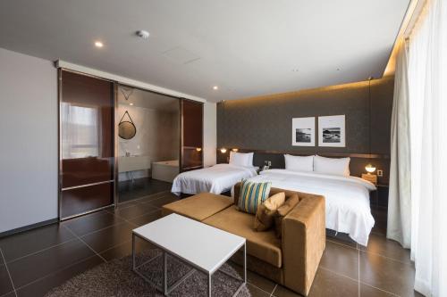 釜山にあるBrowndot hotel Guseoのベッド2台とソファが備わるホテルルームです。