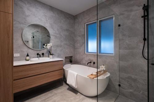 a bathroom with a tub and a sink and a mirror at Sunshine House in Daylesford