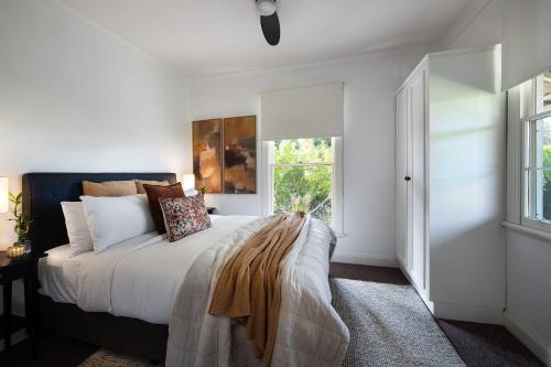 a bedroom with a bed with white walls and a window at Sunshine House, fireplace 4 bedroom & gardens in Daylesford