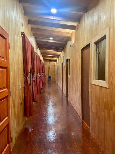 a hallway with wooden walls and a long hallway with red coats at Hostería Lenca in Puerto Montt