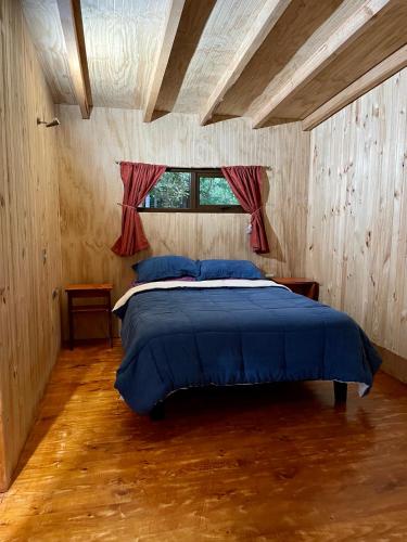 a bedroom with a bed with blue sheets and a window at Hostería Lenca in Puerto Montt