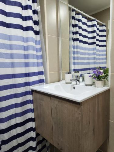 a bathroom sink with a blue and white shower curtain at Departamento full equipado in Temuco
