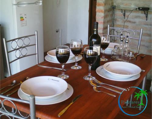 a table with glasses of wine and a bottle of wine at Palmares Apart Termal in Termas de Guaviyu