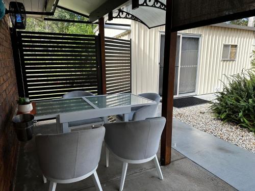 a glass table and chairs on a patio at Luxury Boutique Self-Contained Private Granny Flat in Ormeau