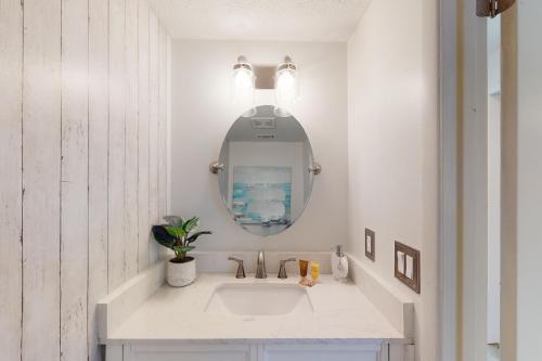 une salle de bain blanche avec un lavabo et un miroir dans l'établissement Sugar Reef Cottage #4, à Fort Walton Beach