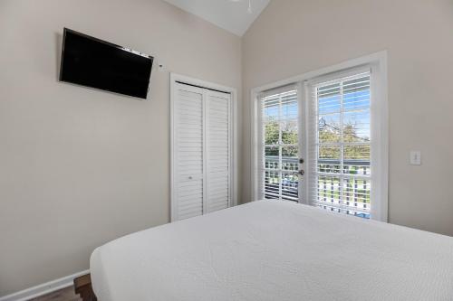 a white bedroom with a bed and two windows at Palm Villa in Duck Key