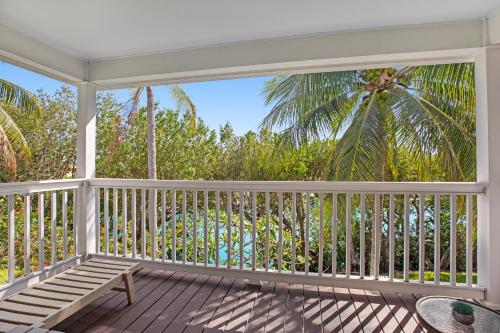 a porch with a bench and a palm tree at Palm Villa in Duck Key