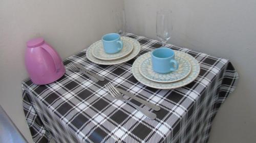 a table with two plates and two cups and a vase at Studio Próximo ao centro in Palmas