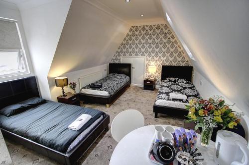 a room with two beds and a table with flowers at Beaconsfield Hotel in London