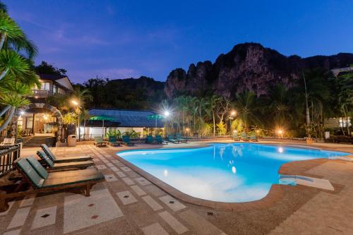 a pool at night with a mountain in the background at Green View Village Resort in Ao Nang Beach