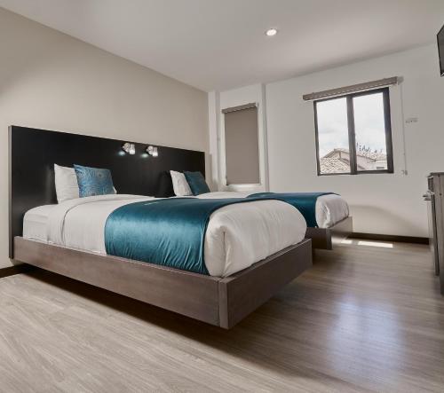 a large bedroom with two beds and a window at Hotel & Suites en Cuenca, Venue Batán in Cuenca