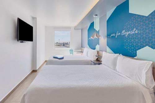 a hotel room with two beds and a tv at One Puebla Angelopolis Periferico in Puebla