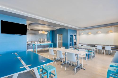 a dining room with blue walls and white tables and chairs at One Puebla Angelopolis Periferico in Puebla