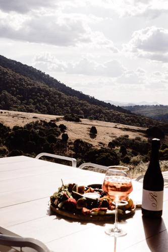 a bottle of wine and a plate of food on a table at Luxury Alpine Stay with Epic Views at Mt Buller foothills in Merrijig