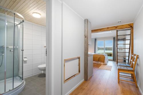 a bathroom with a shower and a toilet and a bedroom at Sveggvika Guesthouse in Averoy