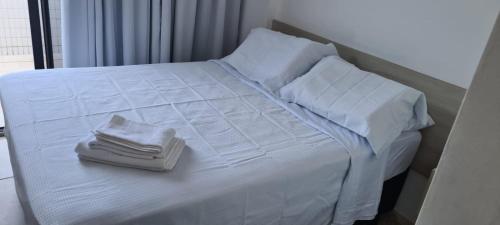 uma cama branca com toalhas e almofadas em MAR DO CABO BRANCO YELLOW residence em João Pessoa