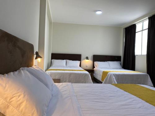 a hotel room with two beds and two windows at Hotel Alba in Ica