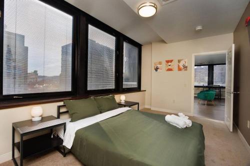 a bedroom with a large green bed with large windows at Luxe City Views in DT Pittsburgh VALET GYM WIFI in Pittsburgh