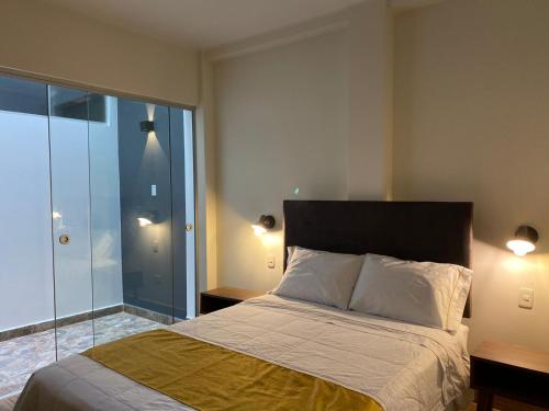 a bedroom with a bed and a glass door at Hotel Alba in Ica