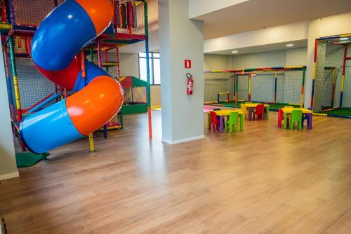 - une aire de jeux avec toboggan dans une pièce dotée de tables dans l'établissement Dall'Onder Planalto Hotel Bento Gonçalves, à Bento Gonçalves