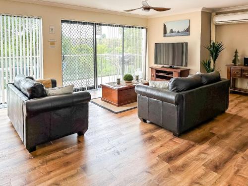 a living room with two couches and a television at Paradiso, 3,4 Laman Street - Comfortable unit with water views, aircon, solar heated pool and in the heart of town in Nelson Bay