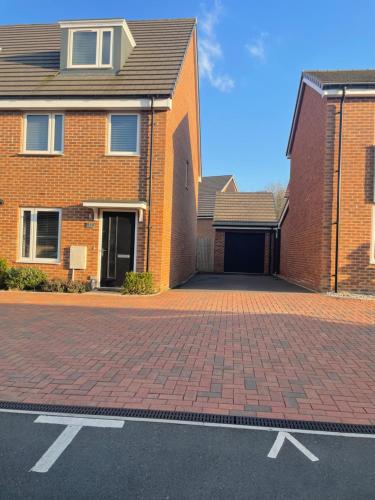 a brick house with a garage and a brick driveway at Deluxe En suite Bedroom with free on site parking in Milton Keynes