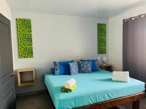 um quarto com uma cama azul com detalhes em azul e verde em Lokai house em Bora Bora